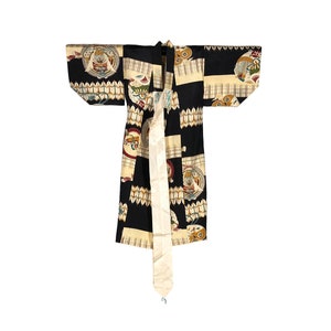 Puede incluir: Un kimono negro y crema con un patrón geométrico y una faja blanca. El kimono tiene un diseño japonés tradicional con círculos y cuadrados.