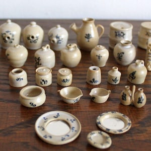 May include: A collection of miniature pottery items in various shapes and sizes, including pitchers, jars, and bowls. The pottery is decorated with a blue and white floral pattern.