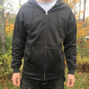 May include: A dark gray zip-up hoodie with a hood and a zipper closure. The hoodie has a pocket on the front and is made of a soft, comfortable fabric.