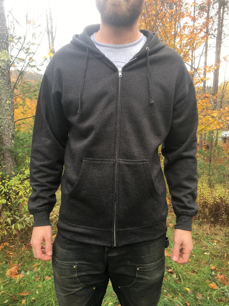 May include: A dark gray zip-up hoodie with a hood and a zipper closure. The hoodie has a pocket on the front and is made of a soft, comfortable fabric.