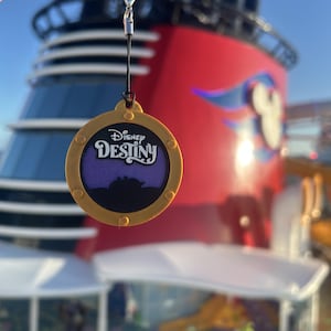 May include: A white ceramic mug with a black handle and the text "But First, Coffee" in a black, bold font. The mug is sitting on a wooden surface. The mug is approximately 4 inches tall.