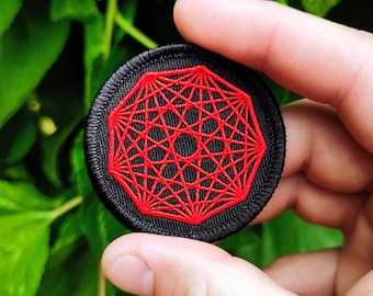 May include: A circular embroidered patch featuring a black fabric base with a vibrant red geometric pattern. The design consists of intricate, intersecting lines forming a complex star-like shape within a circular border, all rendered in red thread.