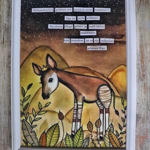 Può includere: Un'illustrazione incorniciata di un okapi con una piccola corona, su uno sfondo di cielo stellato e colline. L'opera include il testo in tedesco: Wahrscheinlich gehören wir wirklich nicht zusammen. Das ist nicht schlimm. An einem Okapi gehört ja auch nichts zusammen, und trotzdem ist es ein unfassbar schönes Tier.