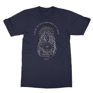 May include: A navy blue t-shirt with a white outline illustration of a woman with a crown of stars and a sun. The text "I spoke to you Aphrodite, in a dream" is written in a circle around the woman. The text "Sappho" is written below the woman.
