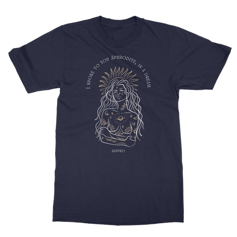 May include: A navy blue t-shirt with a white outline illustration of a woman with a crown of stars and a sun. The text "I spoke to you Aphrodite, in a dream" is written in a circle around the woman. The text "Sappho" is written below the woman.