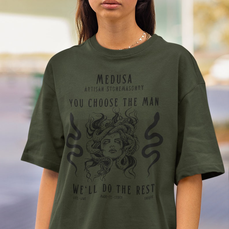 May include: Dark green t-shirt featuring a Medusa graphic with the text "MEDUSA ARTISAN STONEMASONRY YOU CHOOSE THE MAN WE'LL DO THE REST". The design includes a Medusa illustration and two snake illustrations.