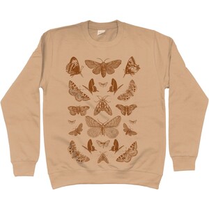 May include: A beige sweatshirt with a pattern of brown butterflies and moths. The design features a variety of butterfly and moth species, including some with intricate wing patterns.