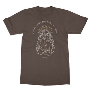 May include: A brown t-shirt with a white line drawing of a woman with a sun halo and celestial tattoos. The text "I spoke to you Aphrodite, in a dream" is written around the woman's head. The text "Sappho" is written below the woman.
