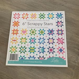 May include: A package of "6" Scrappy Stars" foundation papers for paper piecing. The cover displays a grid of colorful star quilt blocks, each approximately 6 inches square. The brand name "Leila Gardunia" is visible.