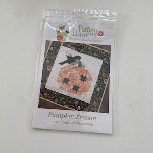 May include: A quilting pattern for a pumpkin with a bird on top. The pattern is called "Pumpkin Season" and is from The Pattern Basket by Margot Languedoc Designs. The pattern is printed on white paper with a black border.