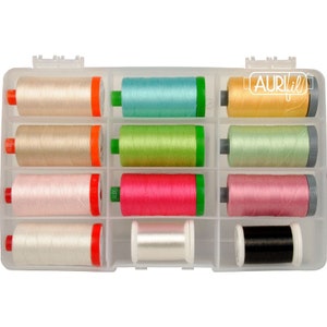 May include: A clear plastic storage case containing eleven spools of Aurifil sewing thread in various colors including beige, turquoise, yellow, light green, pink, white, and black. The spools are arranged in a grid with orange, green, and grey ends.