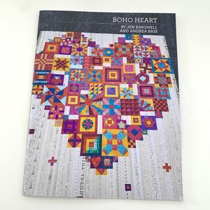 Peut inclure: Une couverture de livre avec le titre "Boho Heart" par Jen Kingwell et Andrea Bair. La couverture présente un cœur en patchwork coloré composé de petits carrés dans différentes nuances de rouge, orange, jaune, bleu, vert et violet.