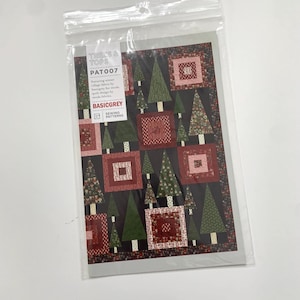 May include: A quilt pattern featuring a black background with green trees and red and pink squares. The pattern is called "Trees & Tops" and the pattern number is "PAT007". The pattern is by BasicGrey Sewing Patterns.
