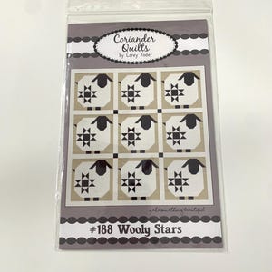 May include: A quilt pattern with a black and white design of stars and sheep. The pattern is called "#188 Woolly Stars" and is from Coriander Quilts by Corey Yoder.