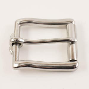 May include: A shiny, silver-colored metal belt buckle. The buckle has a rectangular shape with a curved top and bottom bar. The design includes a central bar and a pin for securing a belt. The buckle is shown against a white background.