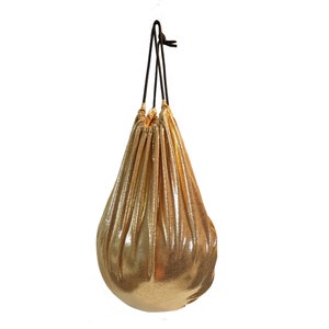 May include: A gold metallic drawstring bag with black drawstrings. The bag is gathered at the top and has a teardrop shape. The fabric has a textured, crinkled appearance.