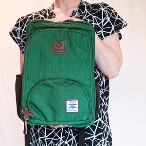 May include: A rectangular green backpack with a brown leather-like patch featuring the text RESILIENCE MEDICAL EQUIPMENT. A smaller white rectangular label at the bottom reads WARNING THIS BAG CONTAINS LIFE SAVING MEDICAL EQUIPMENT RESILIENCE MEDICAL.
