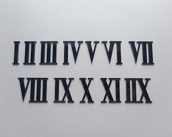 May include: Black Roman numeral clock numbers, I through XII, for a clock face.