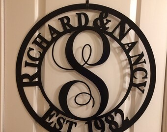 May include: Black metal wreath with the names "Richard & Nancy" and the year "EST 1982" around a large letter "S".