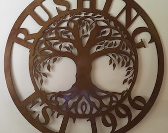 May include: A circular metal sign with a tree of life design and the text "BUSHING EST 1996". The sign is brown and has a rustic look.