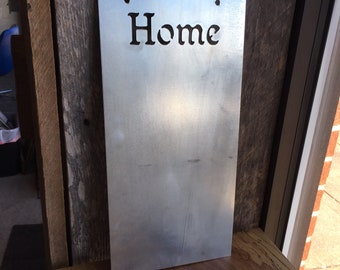 May include: A silver metal sign with the word "Home" cut out in the center. The sign is hanging on a wooden wall.