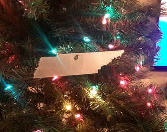 May include: A Christmas tree decorated with colorful lights and a paper ornament shaped like the state of Tennessee.