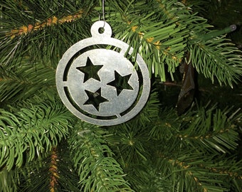 May include: A silver Christmas ornament shaped like a circle with three stars cut out of the center.