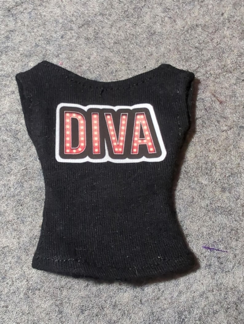May include: Black sleeveless top with the word "DIVA" in a red and white design. The word "DIVA" is in a bold, stylized font with a light-up effect. The top is made of a soft, dark fabric.