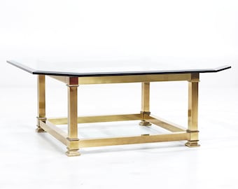 May include: Octagonal glass top coffee table with a brass frame and base. The table has a geometric design and a polished finish.