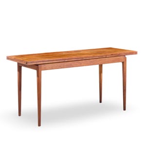 May include: A rectangular wooden table with a light brown finish. The table has a simple design with four slender legs and a tabletop that appears to have an extension. The table is approximately 60 inches long.