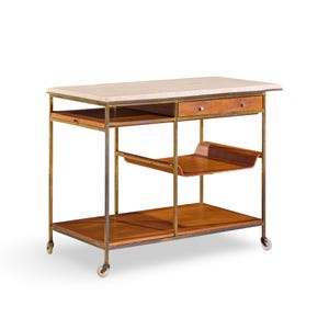 May include: A rolling kitchen island with a light-colored stone countertop, a wooden drawer, and two wooden shelves. The frame is made of metal with a gold finish. The island has a vintage, industrial style.