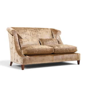 May include: A two-seater sofa upholstered in a shimmering, light brown velvet fabric. The piece features a high, slightly curved backrest, rolled arms, and two rectangular seat cushions. It is supported by four short, dark brown wooden legs.