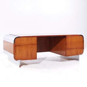 May include: A mid-century modern desk with a wood top and chrome legs. The desk has two drawers on each side and a large open space in the middle.