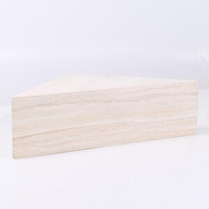 May include: A triangular, light beige travertine coffee table with a smooth, polished surface.