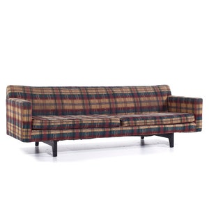 May include: A plaid sofa with a dark wood frame and black legs. The sofa is upholstered in a red, green, and brown plaid fabric.