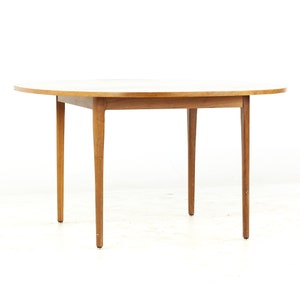 May include: A round, wooden dining table with a white top and four legs. The table is made of solid wood and has a simple, elegant design.