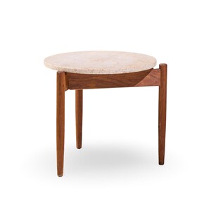 May include: A small, round side table with a light-colored stone top and a dark wood frame. The table has four slender, tapered legs and a simple, mid-century modern design. The table is approximately 20 inches in diameter and 20 inches tall.