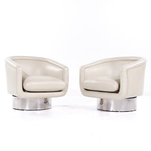 May include: Two swivel chairs with a light gray upholstery and a silver base.