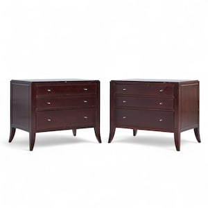 May include: Two matching dark brown wooden dressers with three drawers each. The dressers have silver knobs and are set against a white background. The legs are slightly curved.