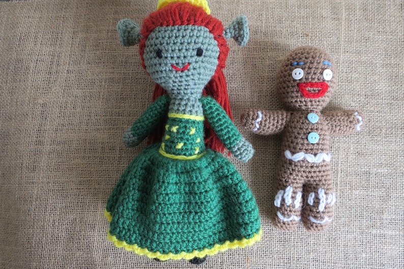 May include: Two crocheted stuffed toys. A green and yellow princess doll with red hair and a brown gingerbread man with white icing.