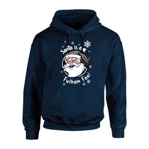 May include: Navy blue hooded sweatshirt with a white graphic of Santa Claus wearing a Fulham FC hat and the text "Santa is a Fulham Fan!" surrounded by snowflakes.