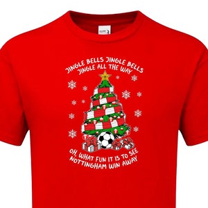 May include: Red t-shirt with a Christmas tree design featuring a soccer ball and the text "Jingle Bells Jingle Bells Jingle All The Way" and "Oh, What Fun It Is To See Nottingham Win Away".