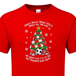May include: Red t-shirt with a Christmas tree design featuring a soccer ball and the text "Jingle Bells Jingle Bells Jingle All The Way Oh. What Fun It Is To See Nottingham Win Away"