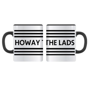 Op de afbeelding: Een witte keramische mok met een zwart handvat en zwarte strepen. De mok heeft de tekst "HOWAY THE LADS" erop gedrukt.