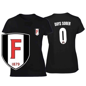 May include: Black t-shirt with a large shield logo featuring a red "F" and the text "1879". The back of the shirt displays "DAYS SOBER" above the number "0". A smaller logo is on the front.