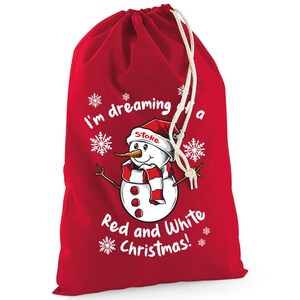 May include: Red Christmas gift bag with a drawstring closure. The bag features a snowman graphic wearing a red and white scarf and hat. Text on the bag reads "I'm dreaming of a Red and White Christmas!"