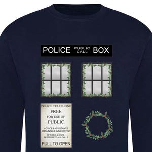 May include: Navy blue sweatshirt featuring a graphic of a police box with the text "POLICE PUBLIC CALL BOX". The design includes two windows, a sign that reads "POLICE TELEPHONE FREE FOR USE OF PUBLIC", and a wreath.
