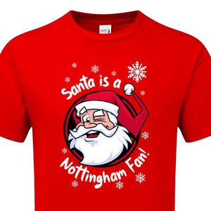 Könnte beinhalten: Rotes T-Shirt mit einer weißen Grafik von Weihnachtsmann, der mit einem roten Hut zwinkert. Der Text "Santa is a Nottingham Fan!" ist auf dem T-Shirt aufgedruckt.