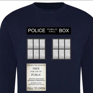 May include: Navy blue sweatshirt featuring a graphic of a police call box. The design includes the words "POLICE PUBLIC CALL BOX" at the top, with two windows and a sign that reads "POLICE TELEPHONE FREE FOR USE OF PUBLIC".