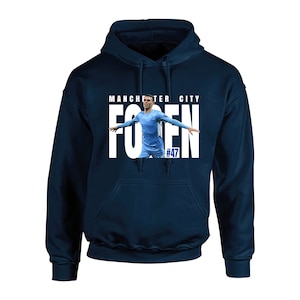 May include: Navy blue hooded sweatshirt featuring a photo of a soccer player with the text "Manchester City" and "Foden #47" in white. The sweatshirt has a front pocket and a drawstring hood.